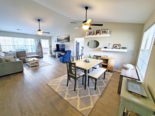 dining area with ceiling fan, hardwood / wood-style floors, lofted ceiling, and a healthy amount of sunlight