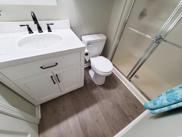 bathroom with toilet, wood-type flooring, vanity, and an enclosed shower