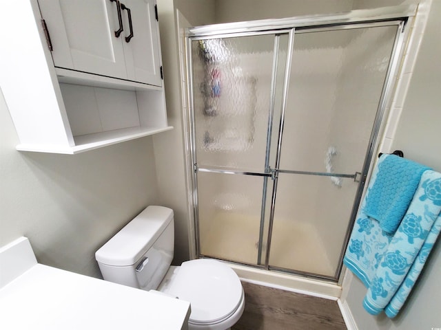 bathroom featuring hardwood / wood-style floors, toilet, a shower with door, and vanity