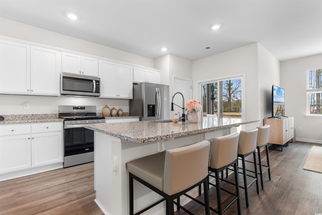 kitchen featuring a kitchen bar, a center island with sink, and stainless steel appliances