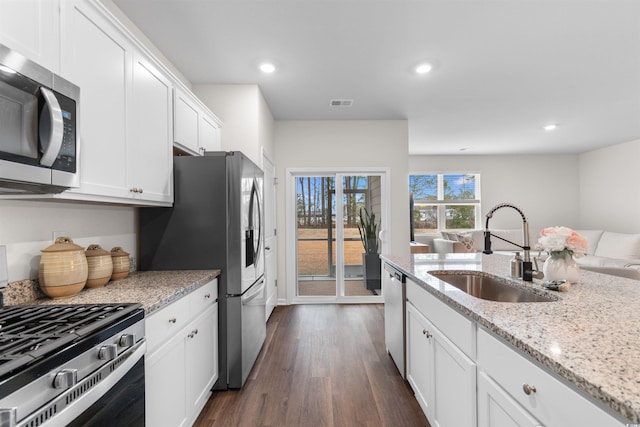 kitchen with dark wood-type flooring, white cabinets, sink, light stone countertops, and appliances with stainless steel finishes