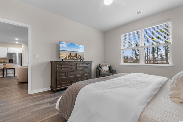 bedroom featuring stainless steel fridge, ceiling fan, and light wood-type flooring