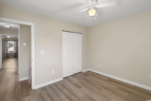 unfurnished bedroom featuring ceiling fan, light hardwood / wood-style flooring, and a closet