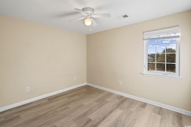 empty room with light wood-type flooring, ceiling fan, and a textured ceiling