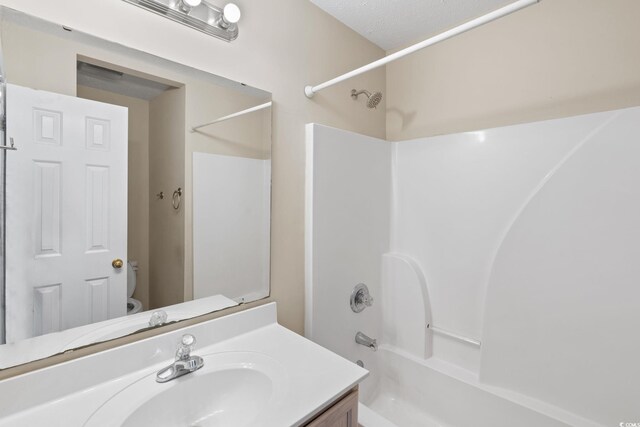 full bathroom featuring toilet, a textured ceiling, shower / tub combination, and vanity