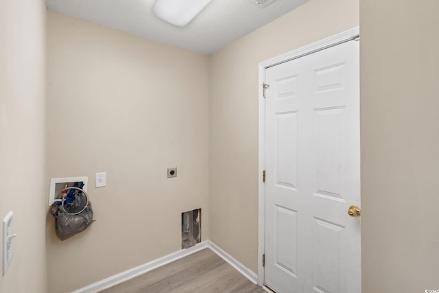 clothes washing area with hookup for a washing machine, hookup for an electric dryer, light hardwood / wood-style flooring, and a textured ceiling