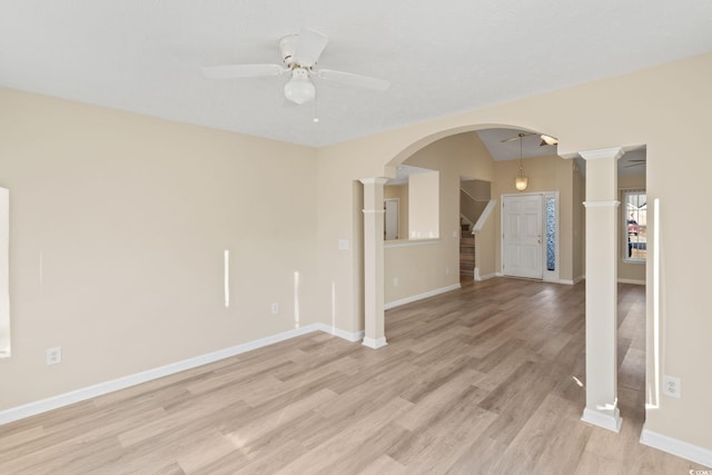 empty room with ceiling fan, light hardwood / wood-style flooring, vaulted ceiling, and decorative columns