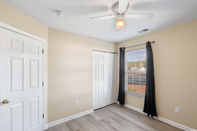 unfurnished bedroom featuring a closet, a textured ceiling, ceiling fan, and light hardwood / wood-style flooring