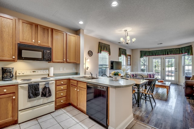 kitchen with kitchen peninsula, sink, black appliances, decorative light fixtures, and an inviting chandelier