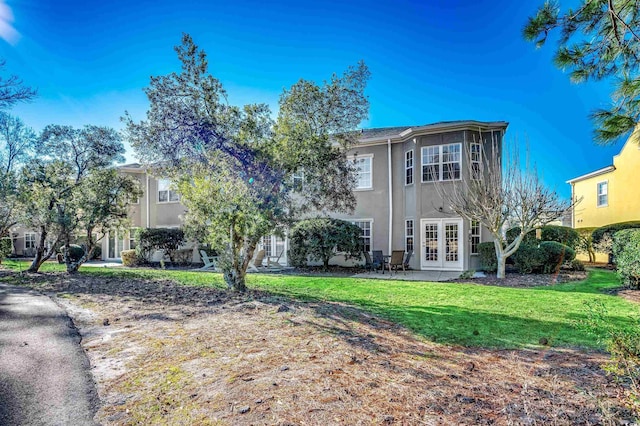 back of property with a lawn and french doors