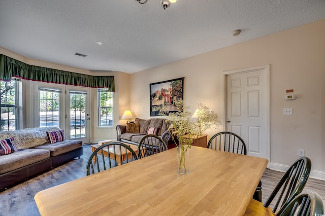 dining space with a textured ceiling and light hardwood / wood-style flooring