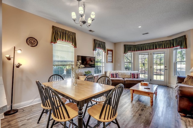 dining room with a notable chandelier, a textured ceiling, and light hardwood / wood-style flooring