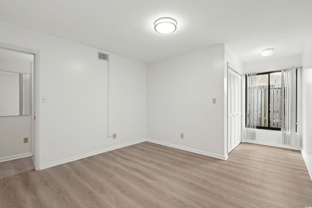 empty room with a textured ceiling and light wood-type flooring