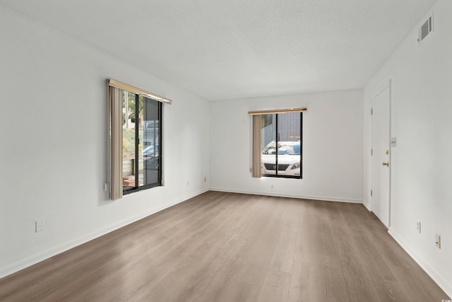 spare room featuring a textured ceiling and light hardwood / wood-style flooring