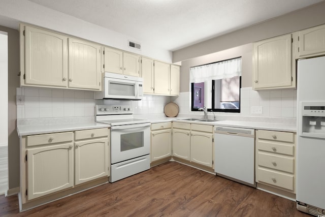 kitchen featuring sink, dark wood-type flooring, white appliances, and cream cabinetry