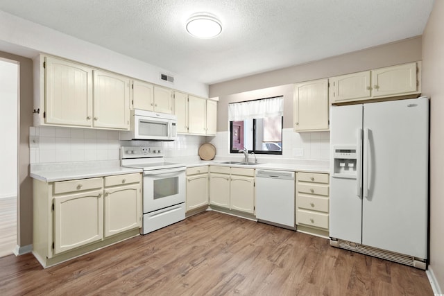 kitchen with sink, light wood-type flooring, backsplash, white appliances, and a textured ceiling