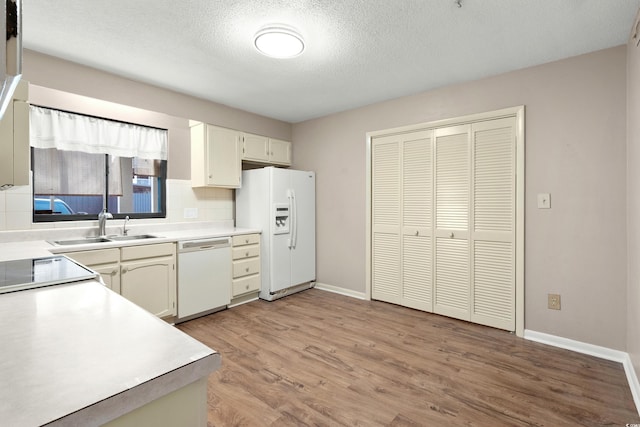 kitchen with sink, backsplash, white appliances, a textured ceiling, and light hardwood / wood-style flooring