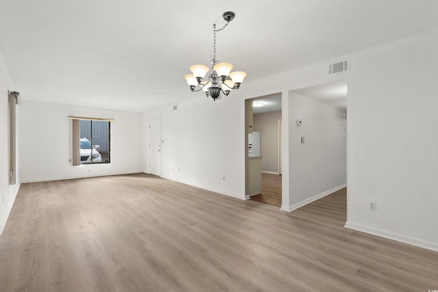 unfurnished room featuring an inviting chandelier and wood-type flooring