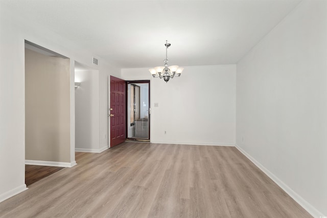 empty room with an inviting chandelier and light wood-type flooring