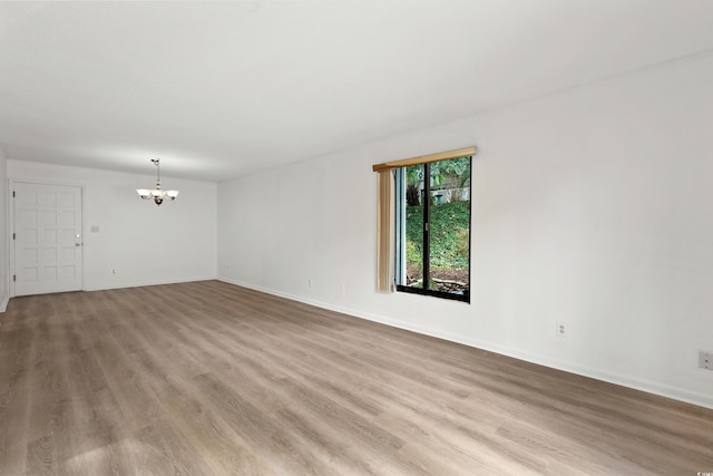 spare room with light hardwood / wood-style floors and a chandelier