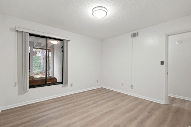 spare room with light hardwood / wood-style floors and a textured ceiling