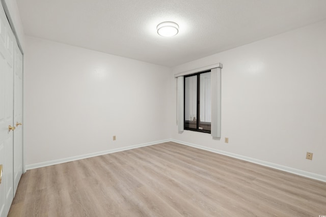 unfurnished room featuring a textured ceiling and light wood-type flooring