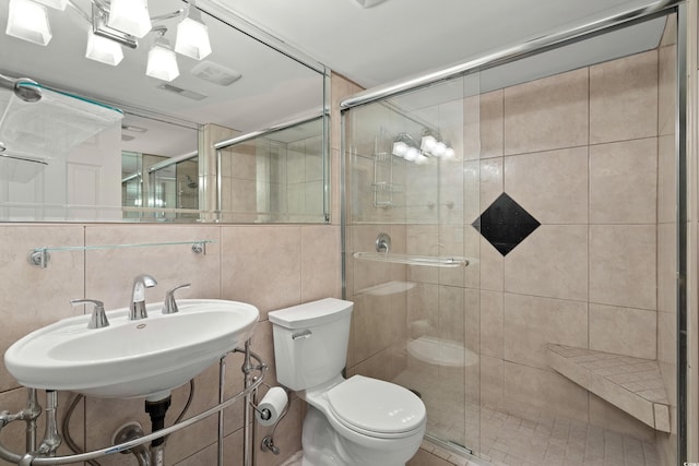 bathroom featuring walk in shower, sink, tile walls, and toilet