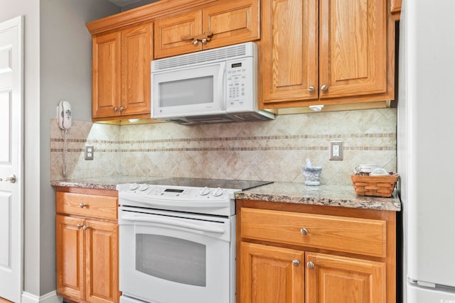 kitchen featuring light stone counters, white appliances, and tasteful backsplash