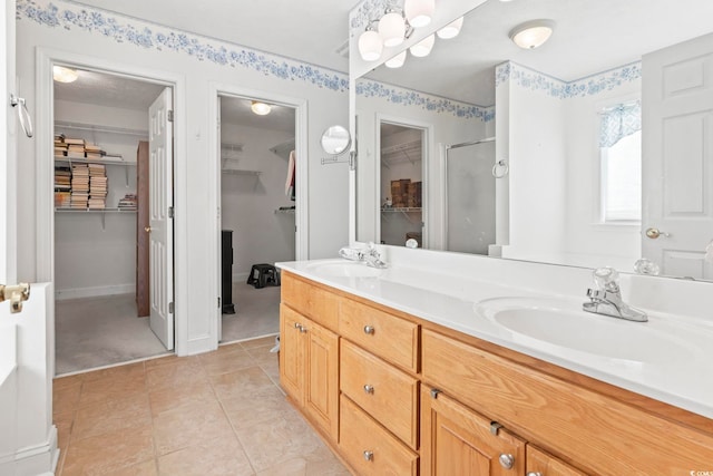 bathroom with a shower with door, vanity, and tile patterned flooring