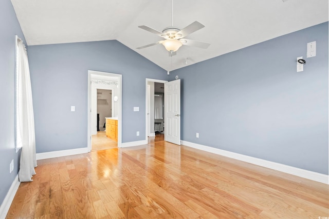 unfurnished bedroom featuring ensuite bath, light hardwood / wood-style flooring, ceiling fan, vaulted ceiling, and a walk in closet