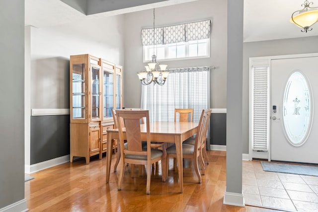 dining room featuring a towering ceiling, a chandelier, and light wood-type flooring