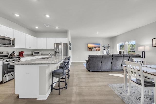 kitchen with sink, white cabinets, a kitchen island with sink, and appliances with stainless steel finishes