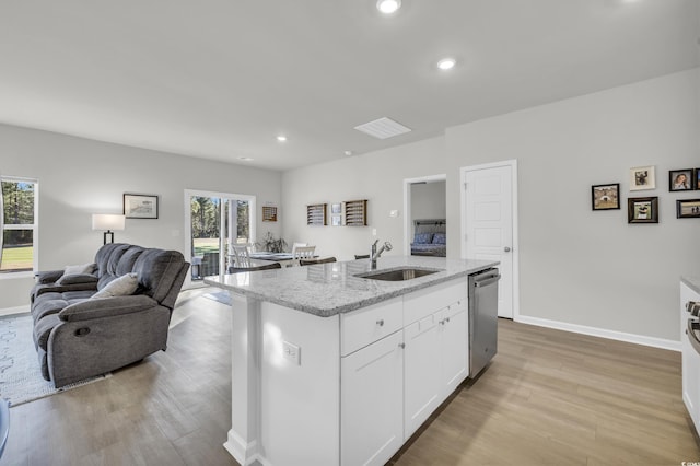 kitchen featuring light stone countertops, stainless steel dishwasher, a kitchen island with sink, white cabinetry, and sink