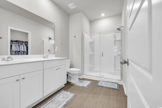 bathroom with toilet, a shower with door, and vanity