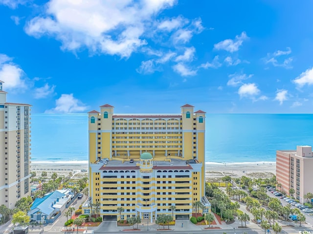 view of building exterior featuring a water view and a beach view