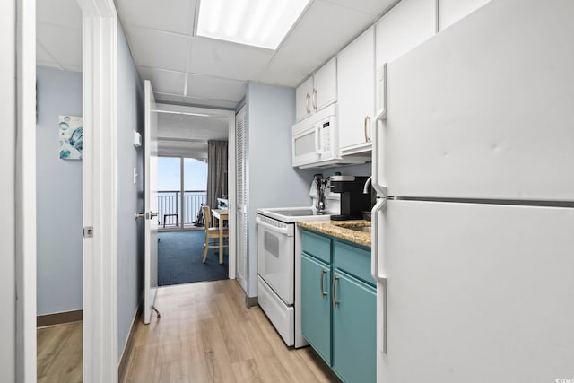 kitchen featuring a drop ceiling, white cabinetry, light wood-type flooring, and white appliances