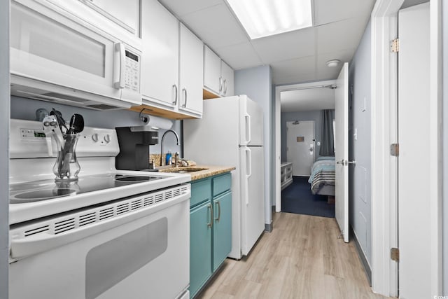 kitchen featuring a drop ceiling, white appliances, sink, light wood-type flooring, and white cabinetry