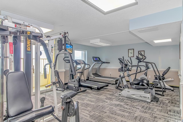 exercise room with carpet floors and a textured ceiling