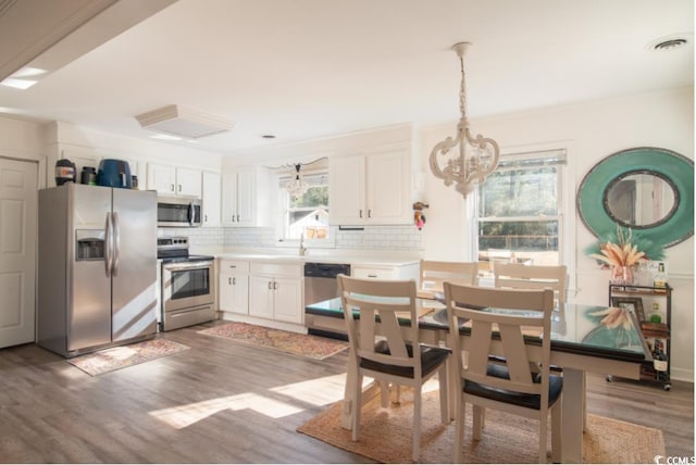 kitchen with decorative light fixtures, white cabinets, stainless steel appliances, and an inviting chandelier