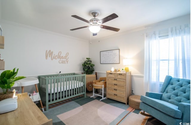 bedroom with ceiling fan, multiple windows, a nursery area, and crown molding