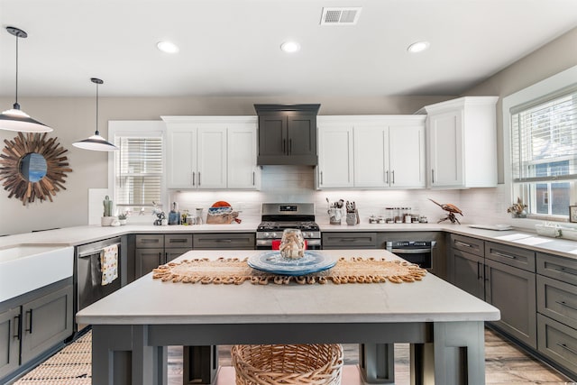 kitchen with stainless steel appliances, tasteful backsplash, pendant lighting, and white cabinets