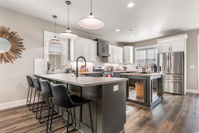 kitchen featuring pendant lighting, a breakfast bar, stainless steel appliances, tasteful backsplash, and white cabinets