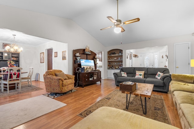 living room featuring lofted ceiling, hardwood / wood-style floors, built in shelves, and ceiling fan with notable chandelier