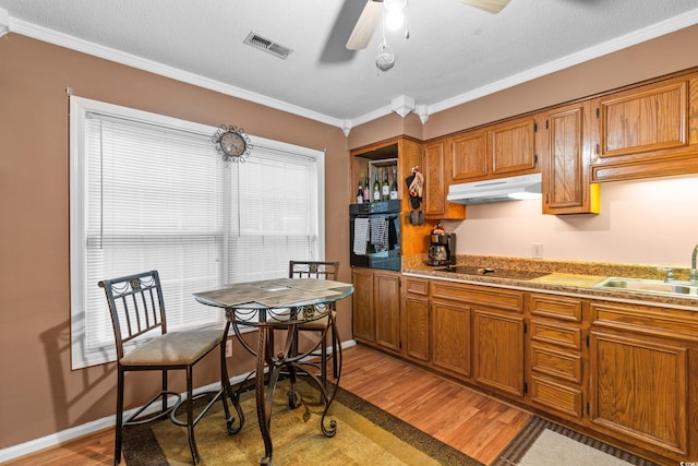 kitchen featuring light wood-type flooring, crown molding, sink, and black appliances