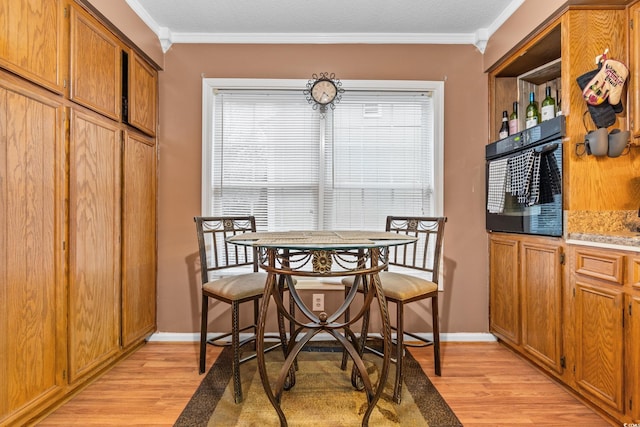 dining space with light hardwood / wood-style flooring and ornamental molding