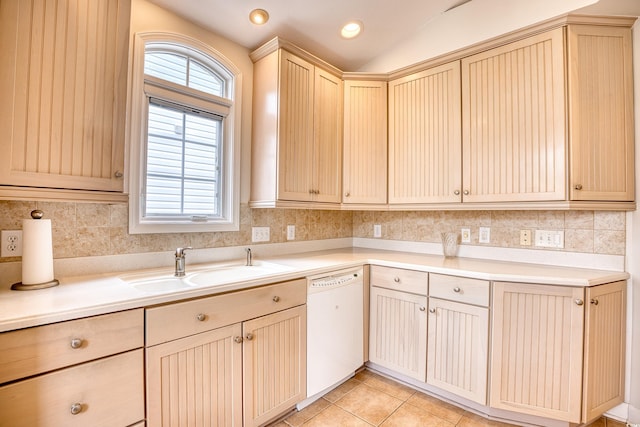 kitchen with light brown cabinets, dishwasher, sink, vaulted ceiling, and light tile patterned floors