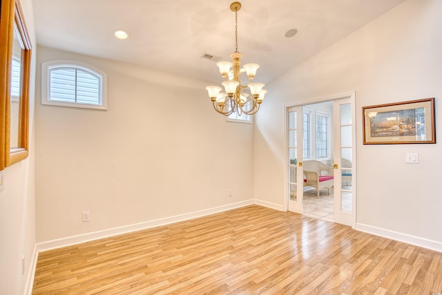 empty room with light hardwood / wood-style floors, vaulted ceiling, and an inviting chandelier