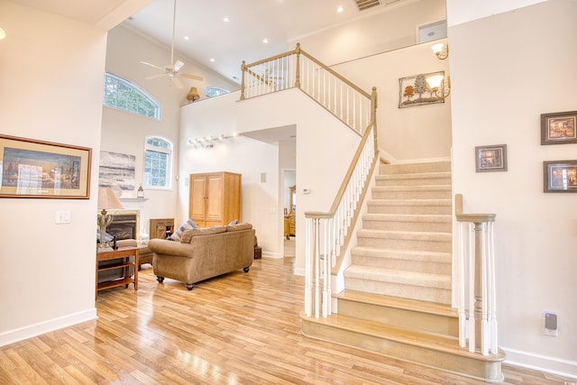 staircase featuring a high ceiling, hardwood / wood-style flooring, and ceiling fan