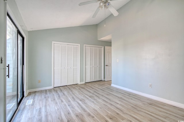 unfurnished bedroom with lofted ceiling, multiple closets, ceiling fan, and light hardwood / wood-style floors