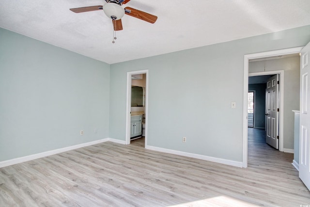 unfurnished bedroom featuring ceiling fan, light wood-type flooring, ensuite bath, and a textured ceiling